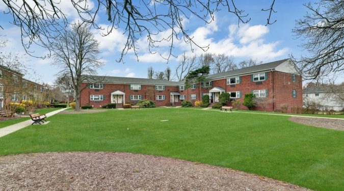 A large lawn with trees and buildings in the background.