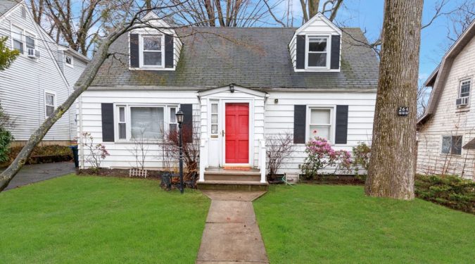 A white house with red door and black shutters.