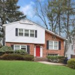 A brick house with red door and white trim.