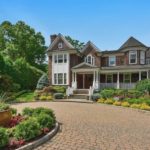 A large house with a driveway and flower garden.