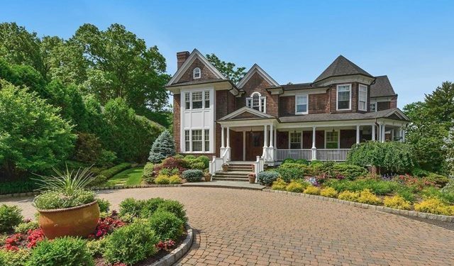 A large house with a driveway and flower garden.