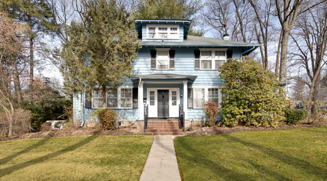 A blue house with a green lawn and trees