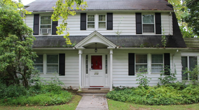 A white house with black shutters and red door.